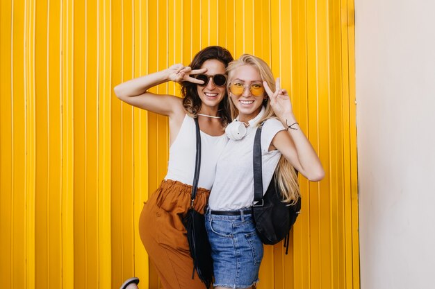 Radosna blondynka w żółtych okularach przeciwsłonecznych wygłupia się z najlepszym przyjacielem.