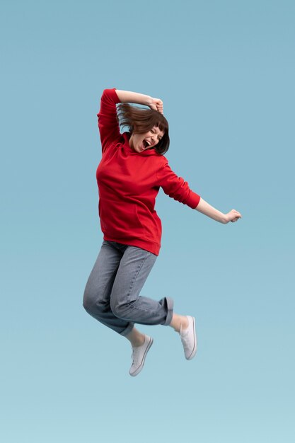 Radosna kobieta skoki na białym tle na niebiesko