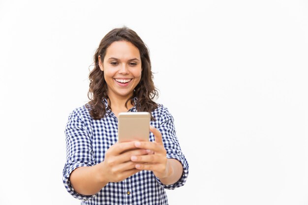 Radosna Łacińska kobieta ogląda śmieszną zawartość z smartphone
