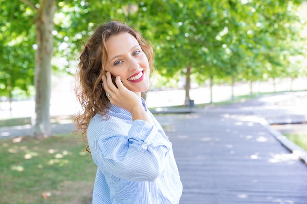 Radosna szczęśliwa dziewczyna mówi na telefonie komórkowym