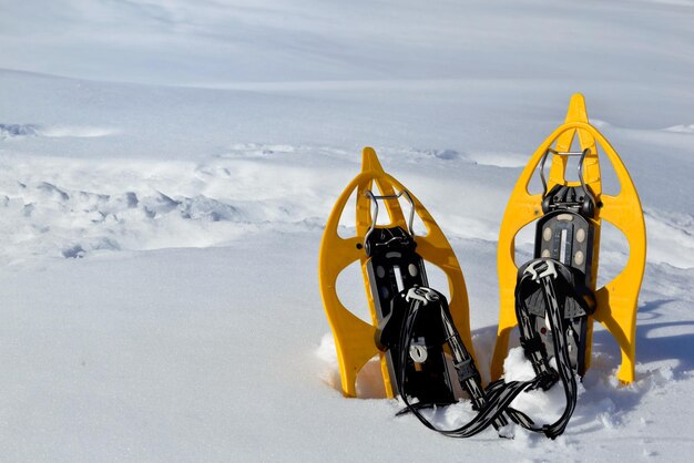 Rakiety śnieżne posadzone w śniegu w górach pod błękitnym niebem