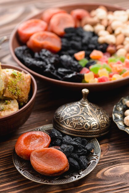 Ramadan suszył surowe organicznie wysuszone owoc w kruszcowym talerzu na drewnianym textured tle