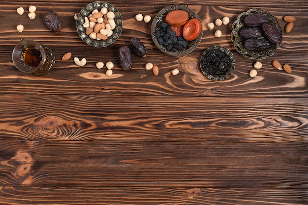 Ramadan świeże daty; suszone owoce; orzechy i ziołowe szkło herbaty na drewniane biurko
