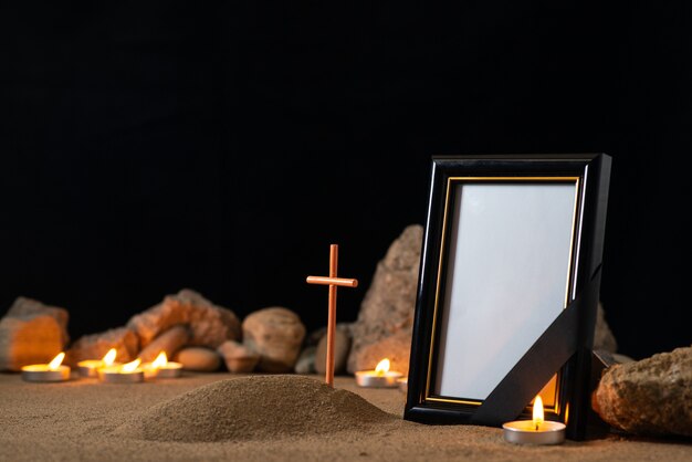 Ramka na zdjęcia z kamieniami, świecami i małym grobem na ciemnej powierzchni