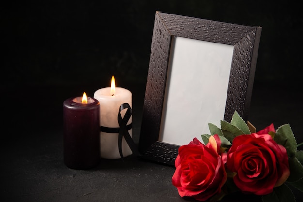 Ramka na zdjęcia z przodu z czerwonymi kwiatami i świecami na ciemnej powierzchni