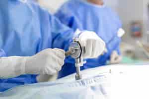 Bezpłatne zdjęcie ręce chirurga z bliska podczas wykonywania zabiegu chirurg używający wiertarki podczas zabiegu lekarze noszą odzież ochronną na sali operacyjnej