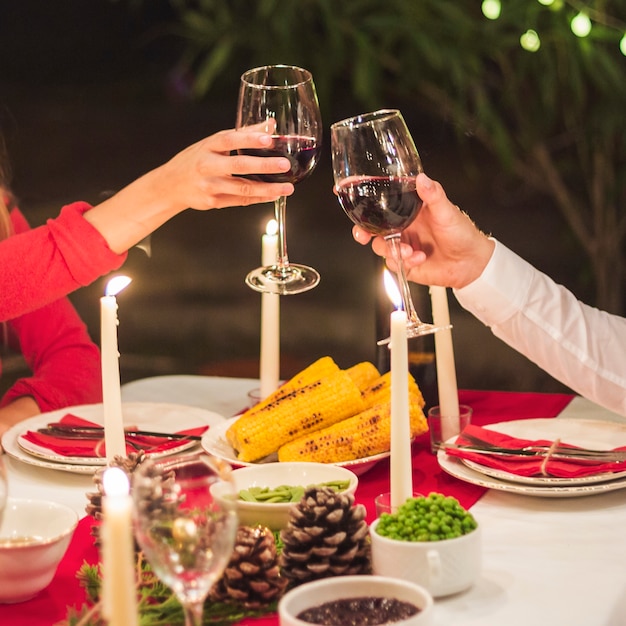 Bezpłatne zdjęcie ręce clinking wineglasses na świąteczny obiad