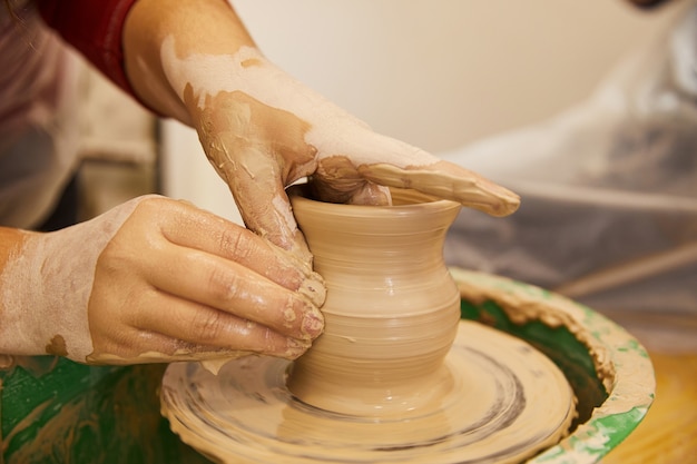 Ręce człowieka kształtują wazon w ceramicznym miejscu pracy