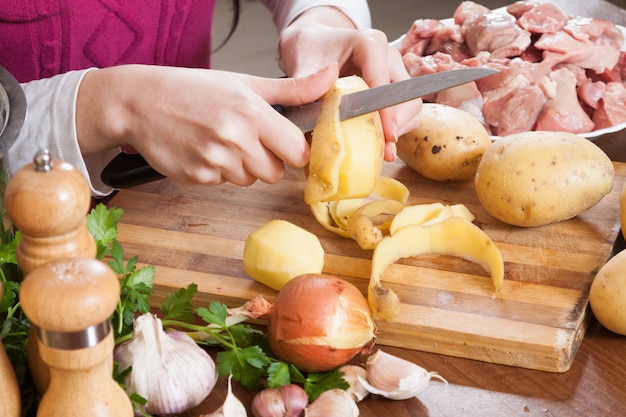 ręce do czyszczenia ziemniaków przy stole w kuchni