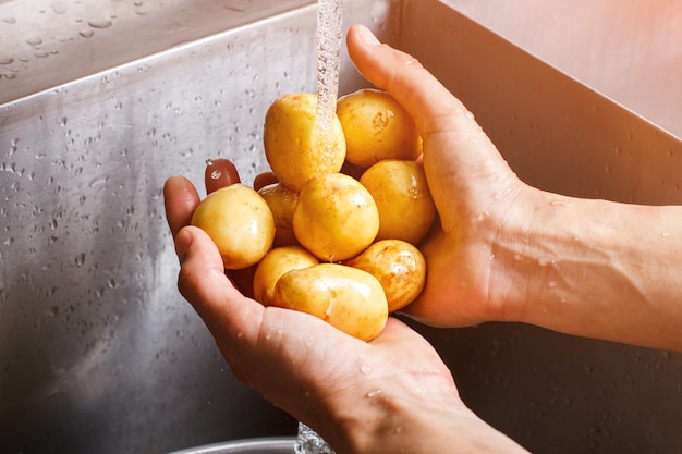 Ręce mężczyzny mycie ziemniaków. młode ziemniaki pod strumieniem wody. składnik zdrowej zupy. warzywa kupione na targu.