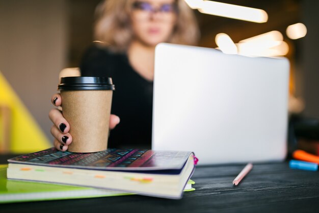 Ręce młoda ładna kobieta siedzi przy stole w czarnej koszuli, pracując na laptopie w biurze współpracującym