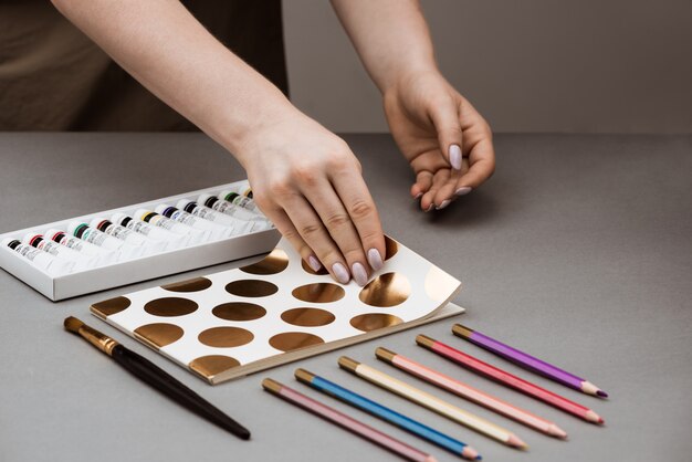 Ręce otwierając szkicownik farbami olejnymi i ołówkami na szary stół