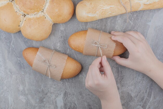 Ręce trzymając mini chleb na powierzchni marmuru