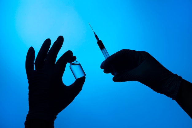 Bezpłatne zdjęcie ręce w ochronnych rękawiczkach trzymające szczepionkę przeciw wirusowi