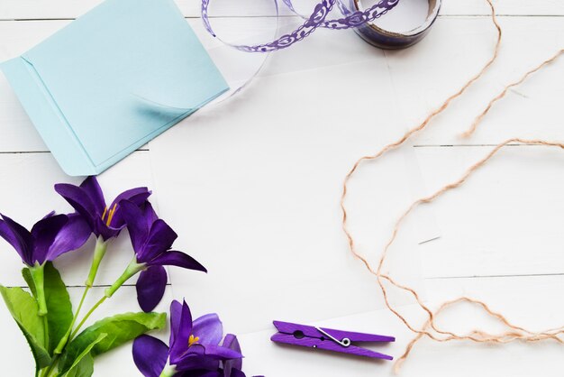 Ręcznie robione sztuczne fioletowe kwiaty; papier; faborek; clothespin i ciąg na tle białej deski