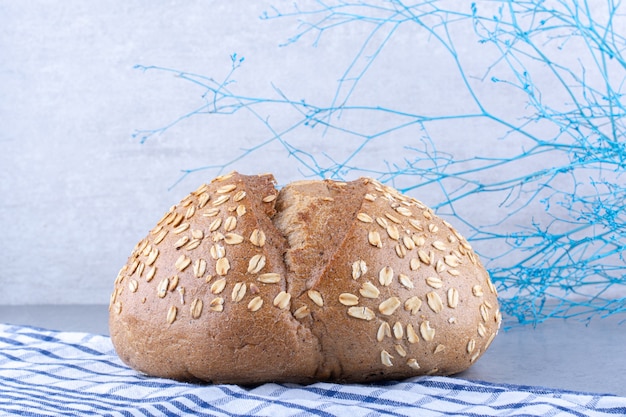 Bezpłatne zdjęcie ręcznik pod chlebem pokrytym płatkami na marmurowej powierzchni