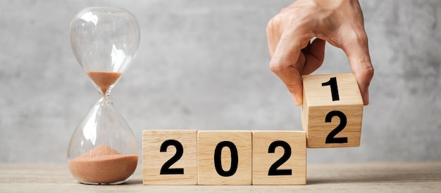Ręczny blok tekstu 2021 do 2022 z klepsydrą na stole. koncepcje rozwiązania, czasu, planu, celu, motywacji, ponownego uruchomienia, odliczania i świąt noworocznych