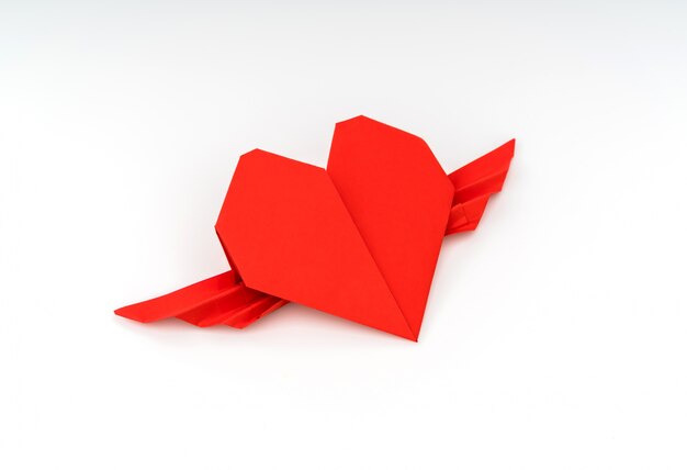 Red papieru origami serce ze skrzydłami na białym tle.