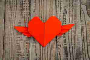 Bezpłatne zdjęcie red papieru origami serce ze skrzydłami na tle drewna.