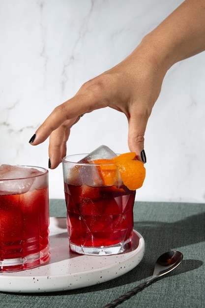 Ręka biorąca kieliszek koktajlowy Negroni