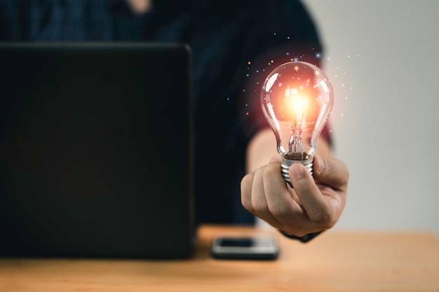 Ręka biznesmena trzymająca żarówkę ze świecącym światłem do kreatywnego inteligentnego myślenia dla inspiracji i innowacji z koncepcją sieci