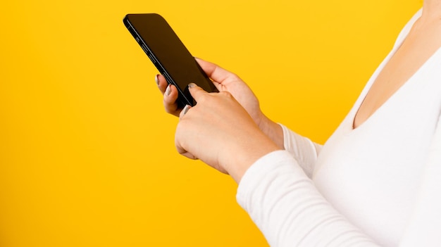 Ręka i smartfon młodej kobiety w bieli trzymającej smartfon czarny ekran i puste miejsce na tekst
