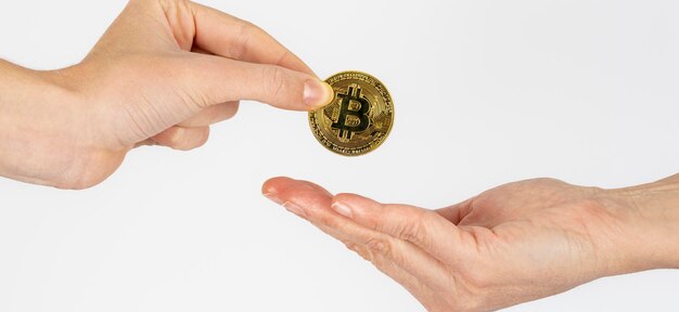 Ręka kobiety daje monetę bitcoin innej kobiecie