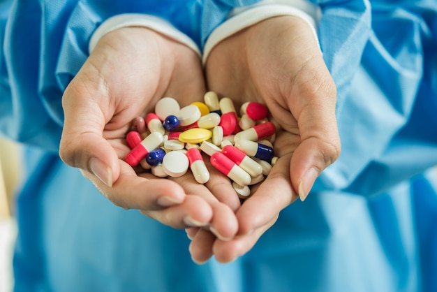 Ręka kobiety wylewa tabletki leku z butelki