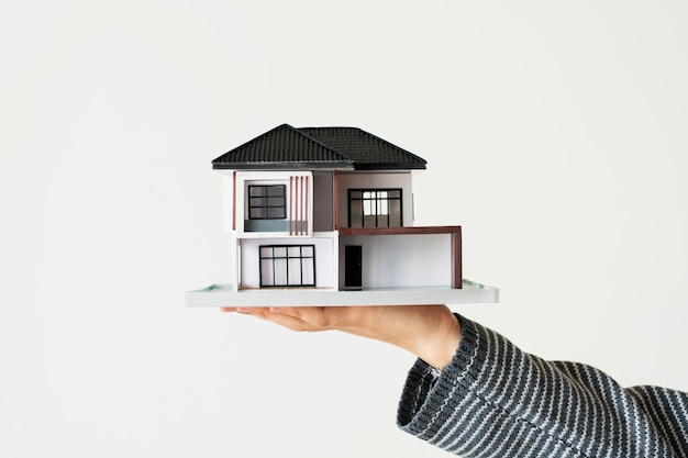 Ręka prezentująca modelowy dom do kampanii kredytów mieszkaniowych