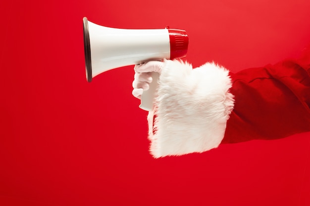 Ręka Świętego Mikołaja trzymająca megafon na czerwono