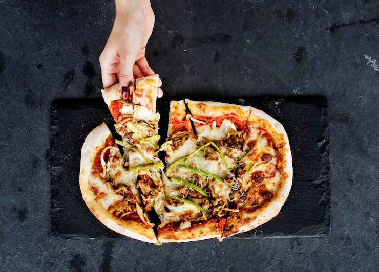 Bezpłatny plik Zdjęcie ręka trzyma kawałek pizzy