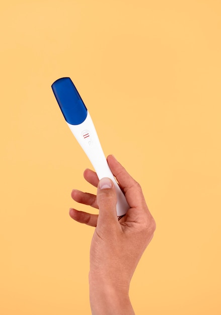 Bezpłatne zdjęcie ręka trzyma pozytywny test ciążowy