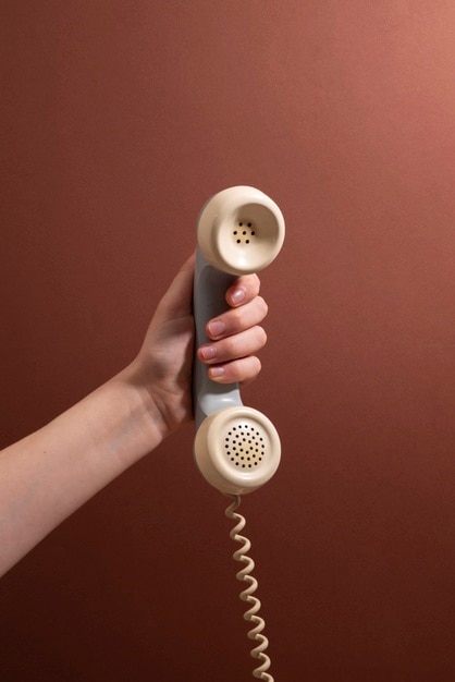 Bezpłatny plik Zdjęcie ręka trzyma telefon z brązowym tłem