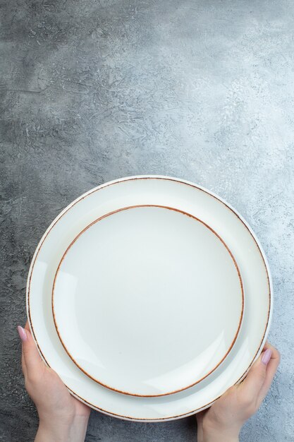 Ręka trzymająca białe talerze na szarej powierzchni z trudną gruboziarnistą powierzchnią gradientową