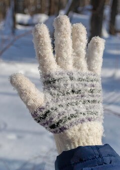 Ręka w rękawiczkę pokrytą płatkami śniegu w zimowy dzień