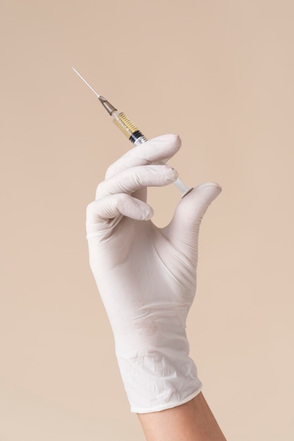 Bezpłatne zdjęcie ręka z lateksową rękawiczką trzymającą strzykawkę ze szczepionką