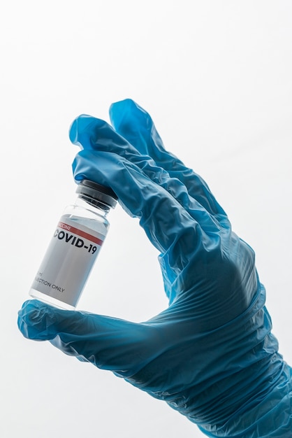 Bezpłatne zdjęcie ręka z rękawiczką trzymająca fiolkę ze szczepionką