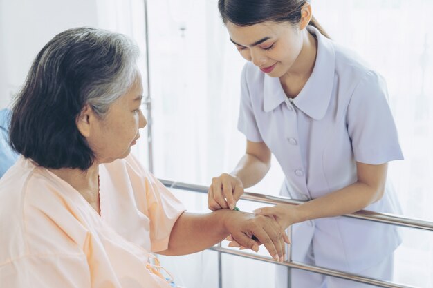 Ręki pielęgniarki mienia pigułka dla wstrzykiwać starsze żeńskie pacjentki kłama na łóżku z ono uśmiecha się, kopii przestrzenią, zdrowym i medycznym pojęciem