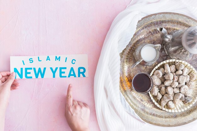 Ręki z Islamskim nowego roku papierem przy tacą z gorącym napojem