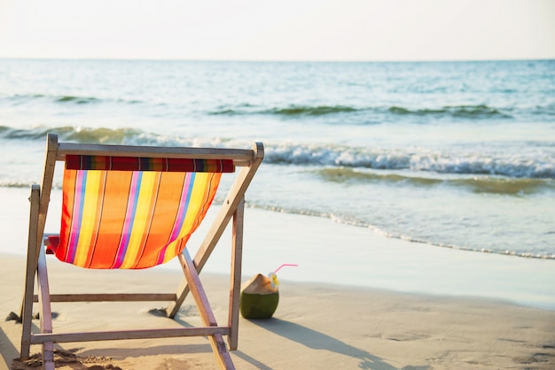 Relaks krzesło plażowe ze świeżym kokosem na czystej, piaszczystej plaży z błękitnym morzem i czystym niebem - morze natury relaks koncepcji