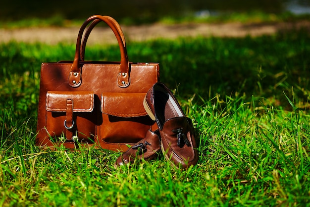 Bezpłatne zdjęcie retro brązowe buty i skórzana torba mężczyzny w jasnej kolorowej letniej trawie w parku