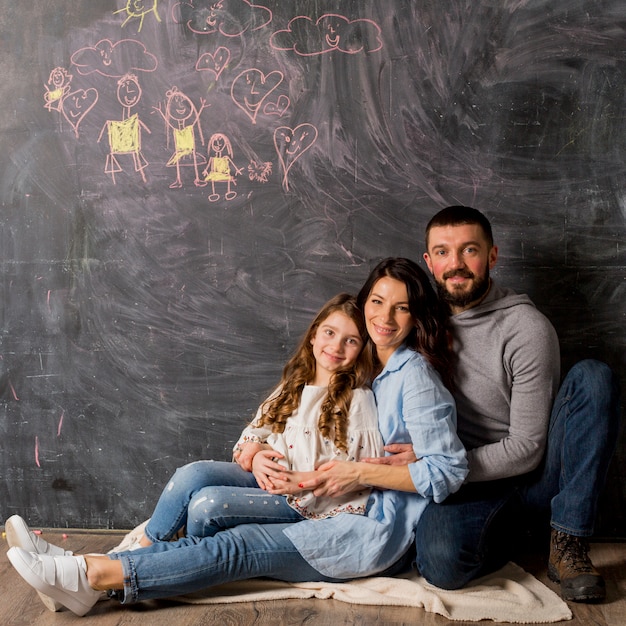 Rodzice z córką ściska blisko blackboard z rysunkiem