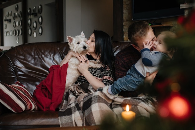 Bezpłatne zdjęcie rodzice z dzieckiem na boże narodzenie i psa siedzącego na kanapie