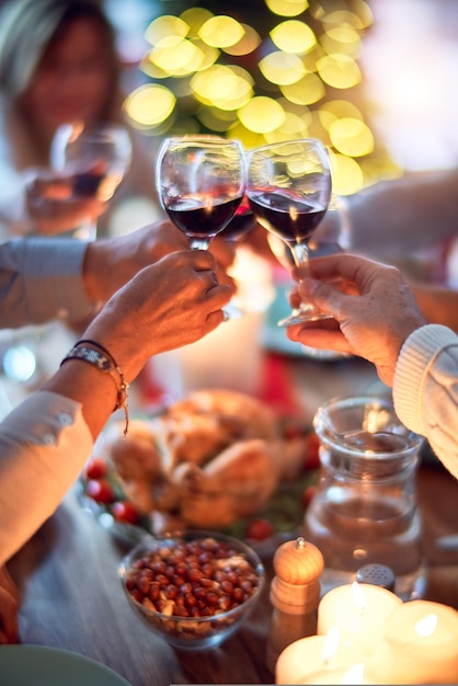 Bezpłatne zdjęcie rodzina i przyjaciele jedzą w domu świętując wigilię z tradycyjnym jedzeniem i dekoracjami, wszyscy siedzą na stole razem wznosząc toast