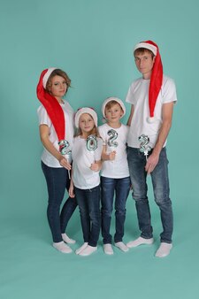 Rodzina matka ojciec córka syn w koszulkach i czapkach mikołaja trzymający w rękach numery 2022