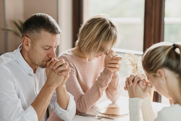 Rodzina modli się razem przed jedzeniem w pomieszczeniu
