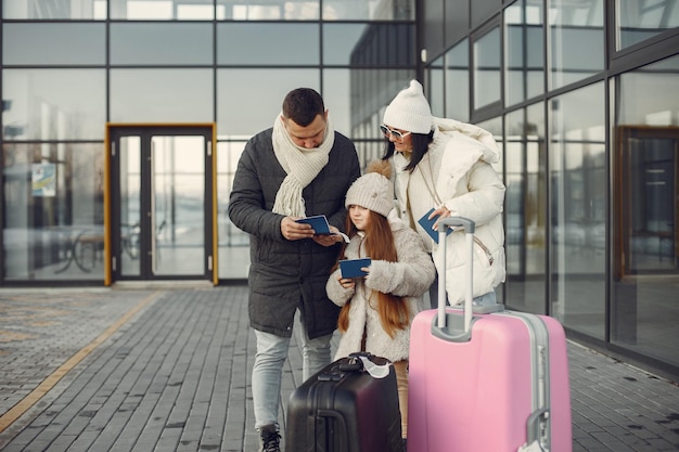 Rodzina stojąca na zewnątrz z bagażem i sprawdzająca paszporty