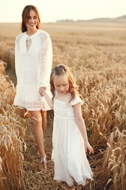 Rodzina w letnim polu. Zmysłowe zdjęcie. Śliczna mała dziewczynka. Kobieta w białej sukni.