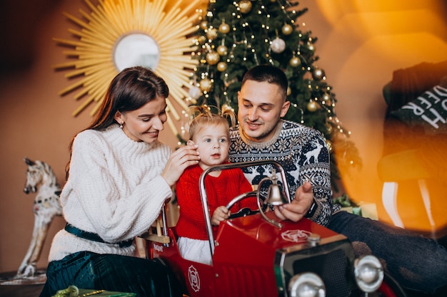 Bezpłatne zdjęcie rodzina z małą córeczką z prezentem świątecznym przez choinkę