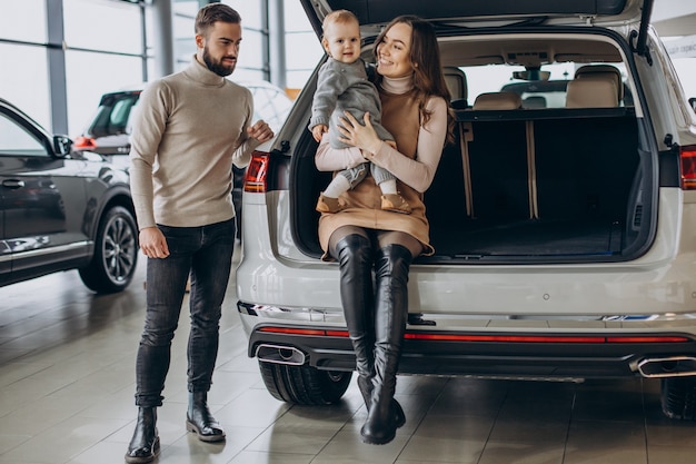 Rodzina z małą dziewczynką wybierającą samochód w salonie samochodowym